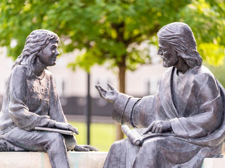 耶稣和一个学生在长凳雕像上